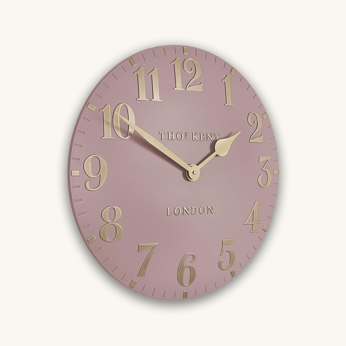 Pink wall clock with gold numbers and 'Thomas Kent London' branding on a light pink background