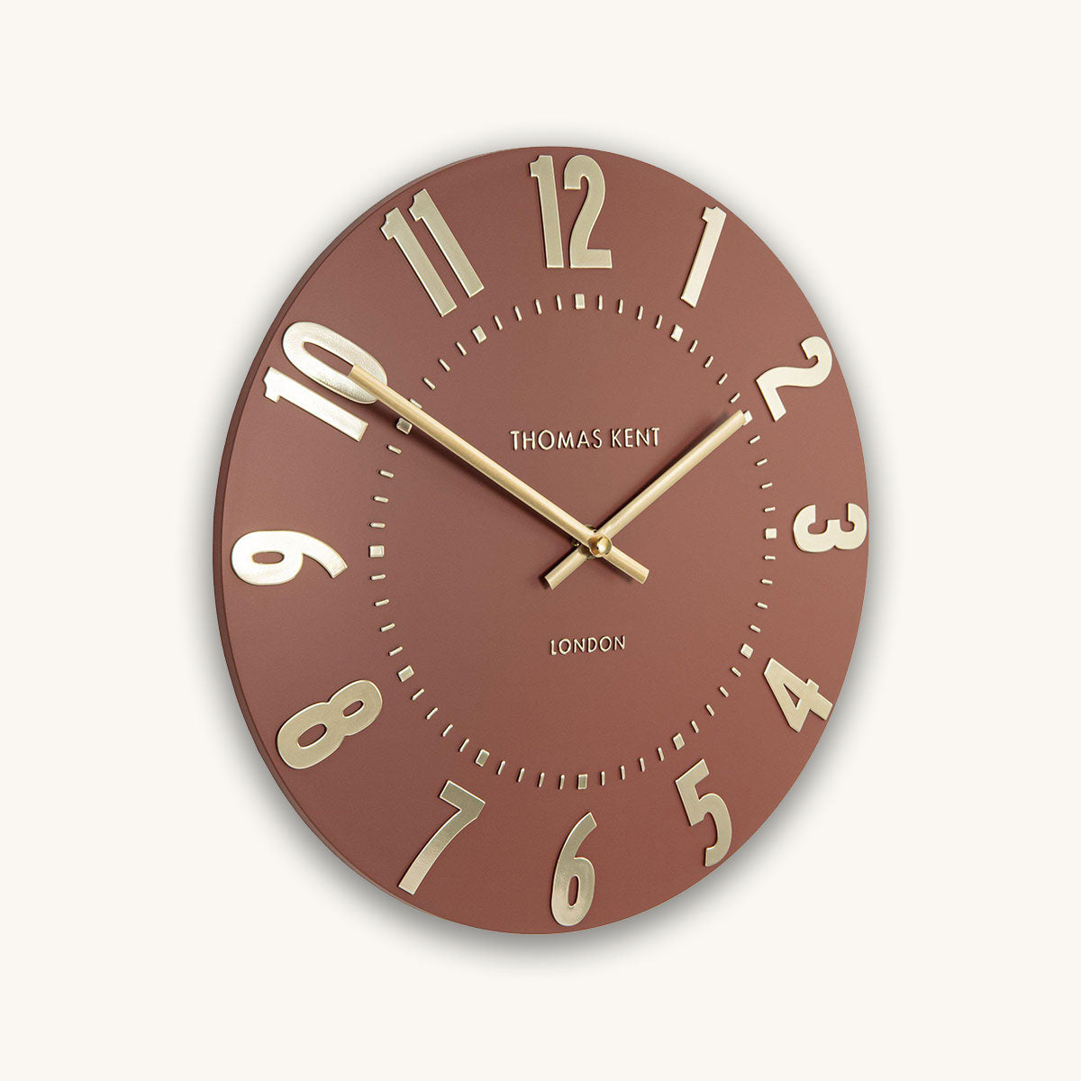 Pale red wall clock with gold numbers and hands on a white background