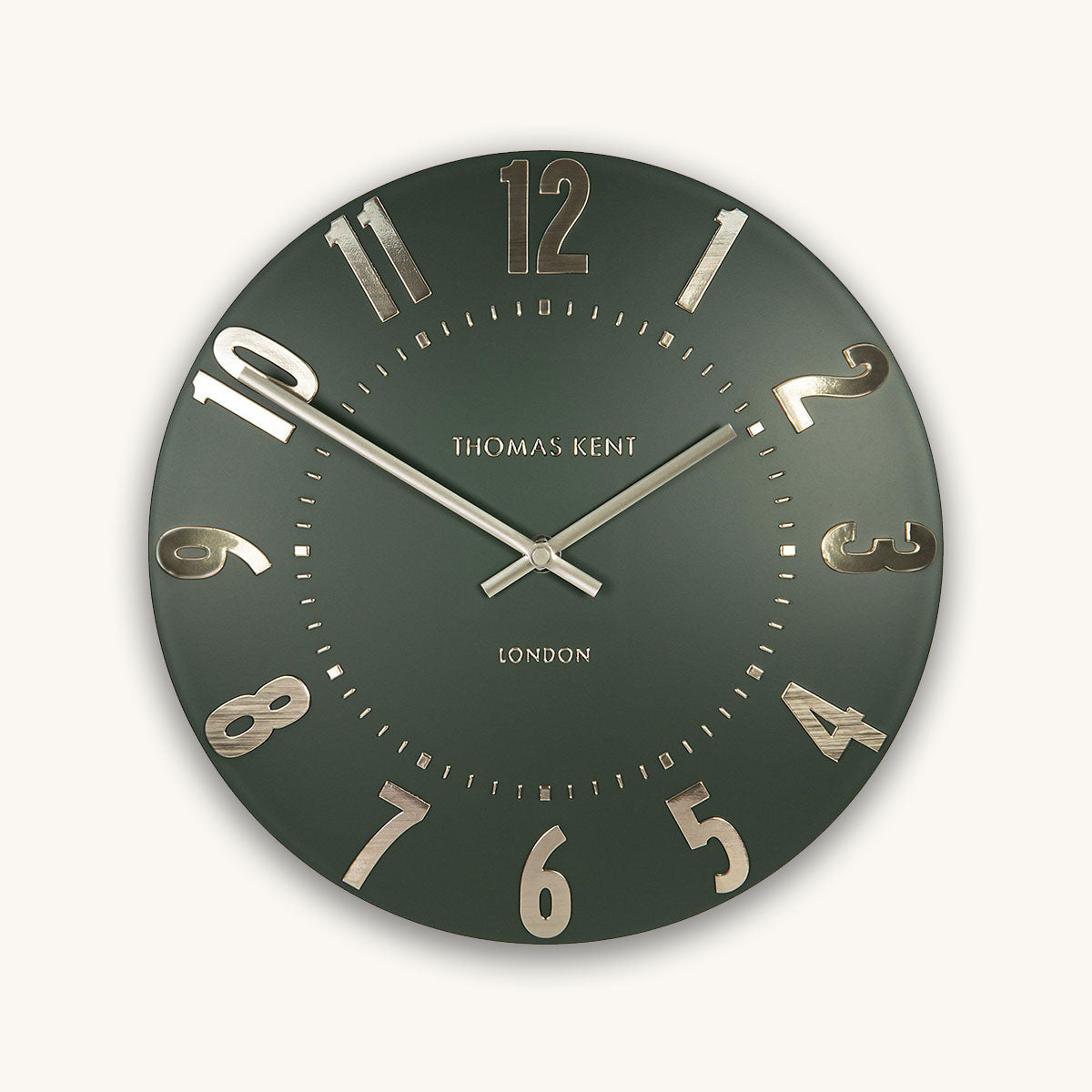 Green wall clock with gold numbers and brand name on a white background