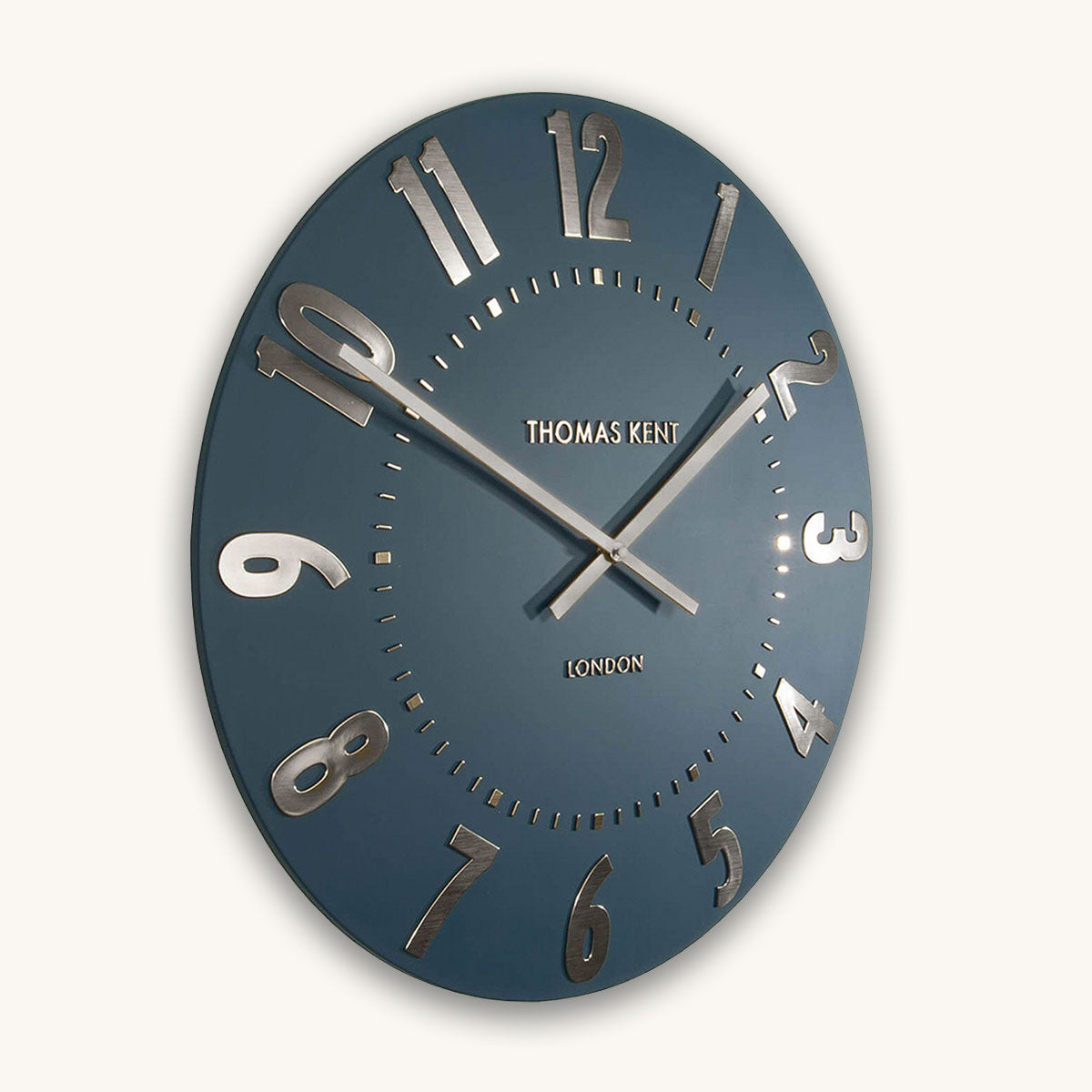 Blue wall clock with silver numbers and hands on a white background