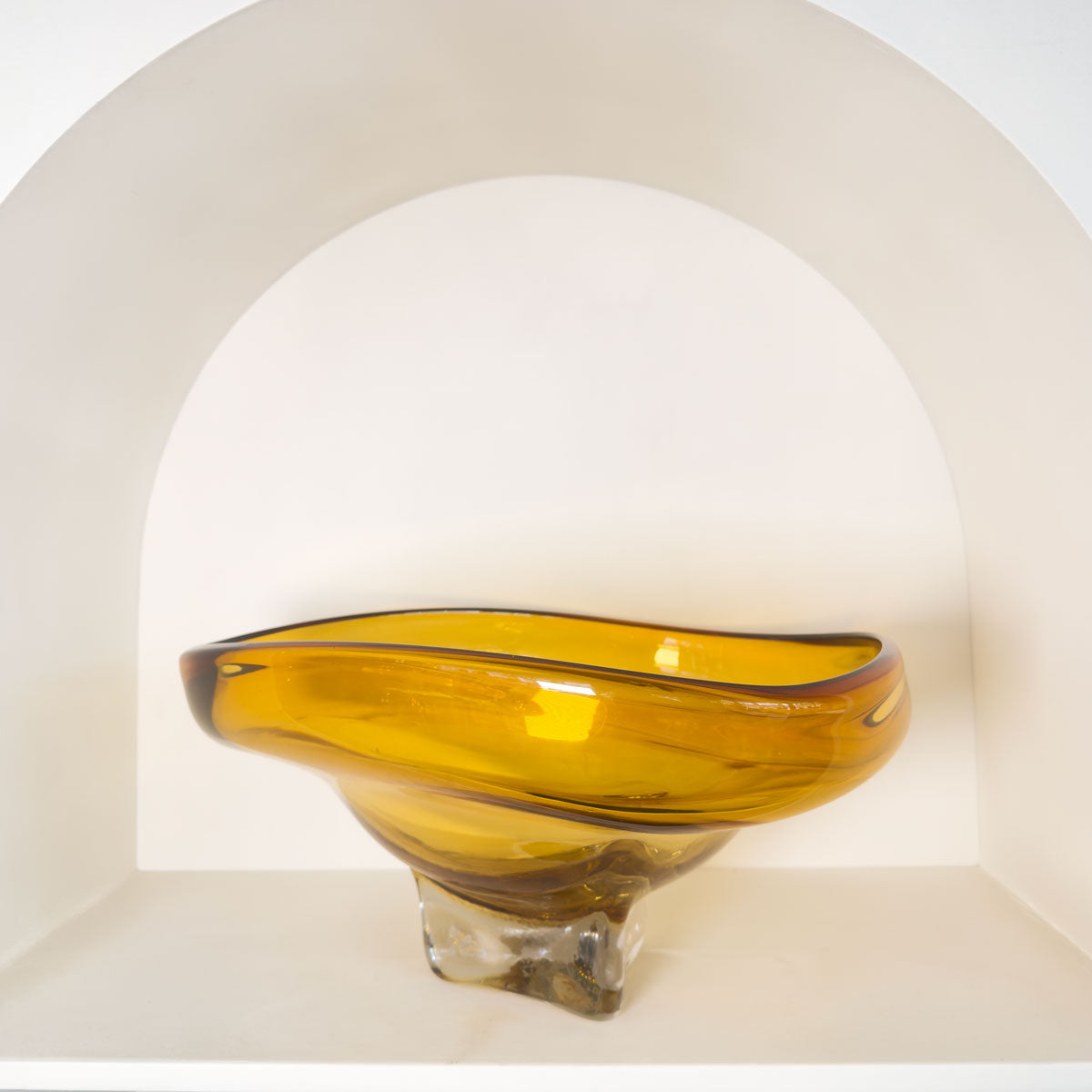 Glass bowl with amber-colored interior and clear base on a white background