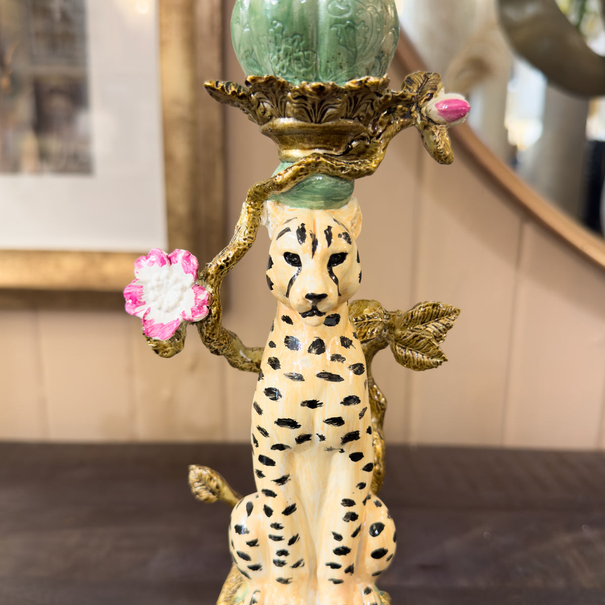 Decorative candle holder with cheetah design and floral elements on a blurred background