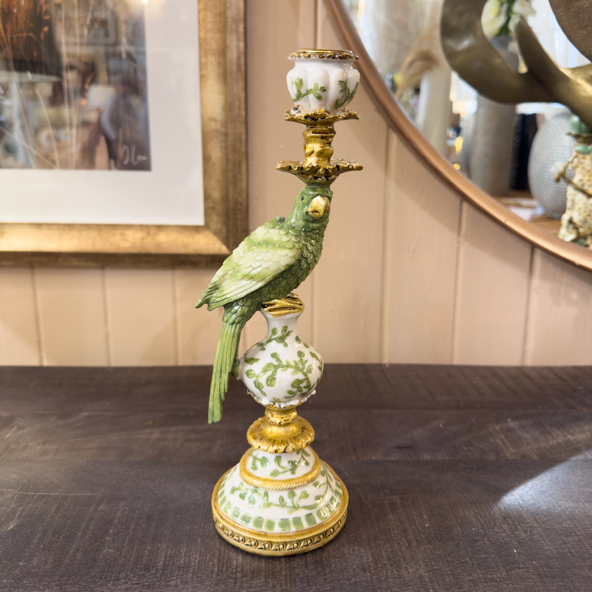 Decorative candle holder with a parrot design on a wooden sideboard.