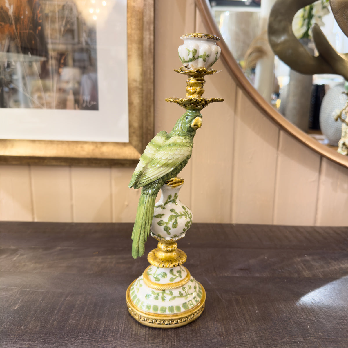 Decorative candlestick with a parrot figure on a wooden surface