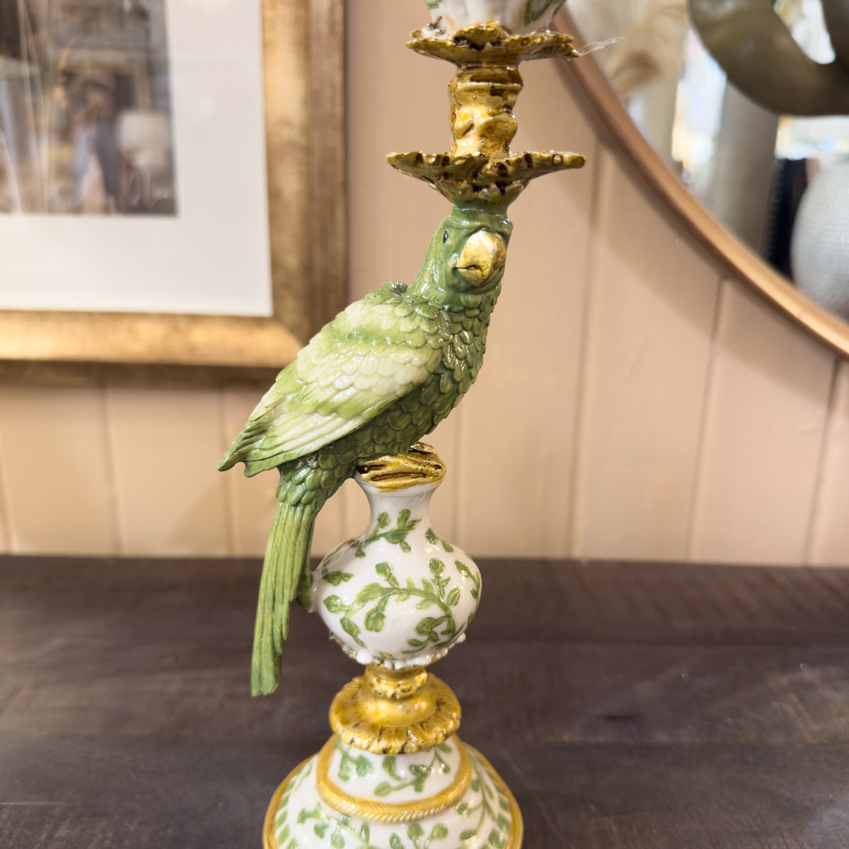 Decorative parrot candle holder with a green parrot figure on a table.