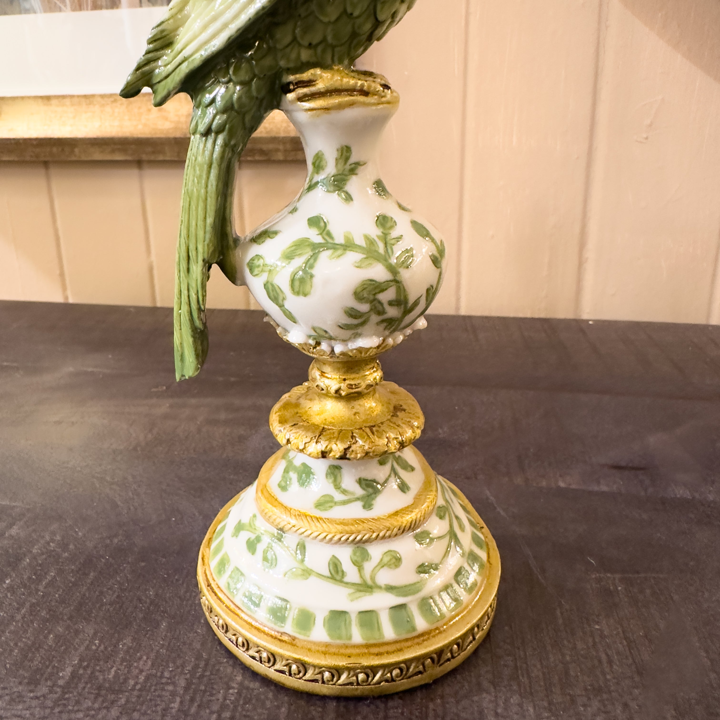 Decorative parrot candlestick with green leaf design on a dark surface