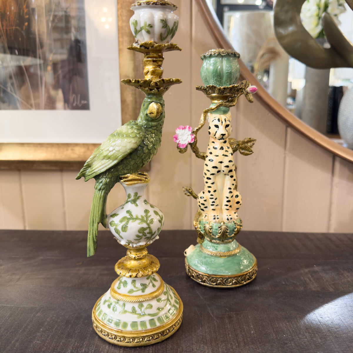 Decorative candle holders with parrot and cheetah design on a wooden surface.