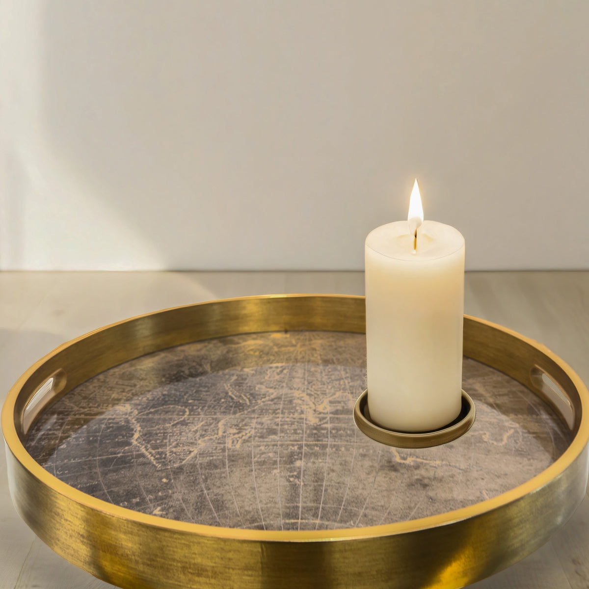 A gold tray with a metallic gold atlas map pattern, sitting on a cream table top.