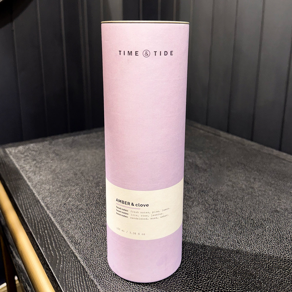 Purple cylindrical product packaging with 'Time & Tide' branding on a dark surface.