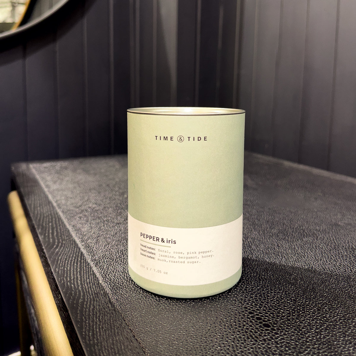 Candle labeled 'Time & Tide' on a dark surface