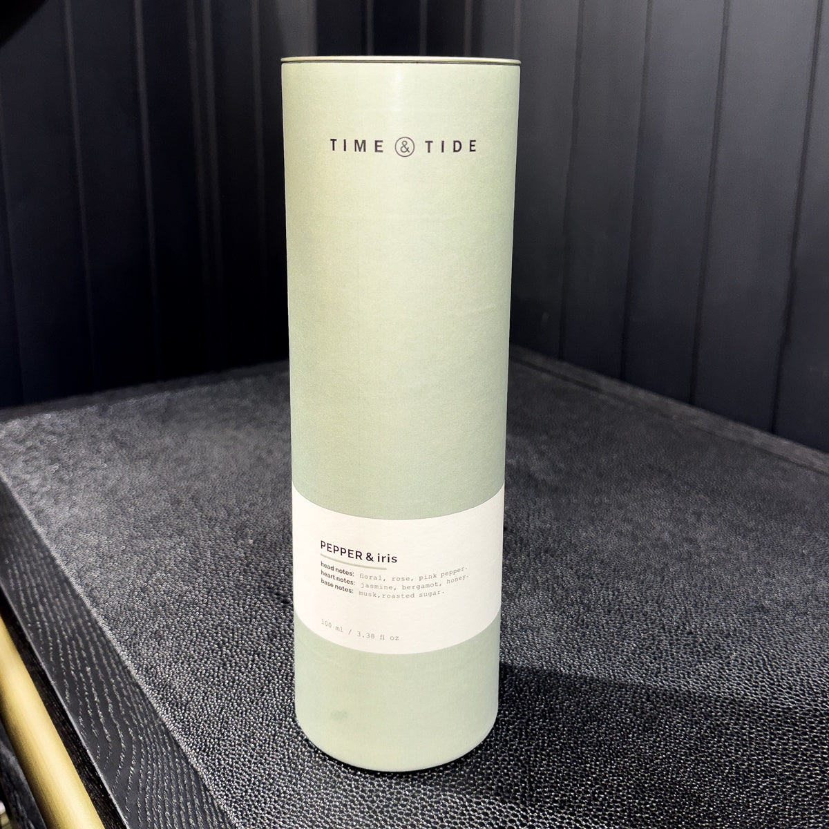 Cylindrical product packaging with 'Time & Tide' branding on a dark surface