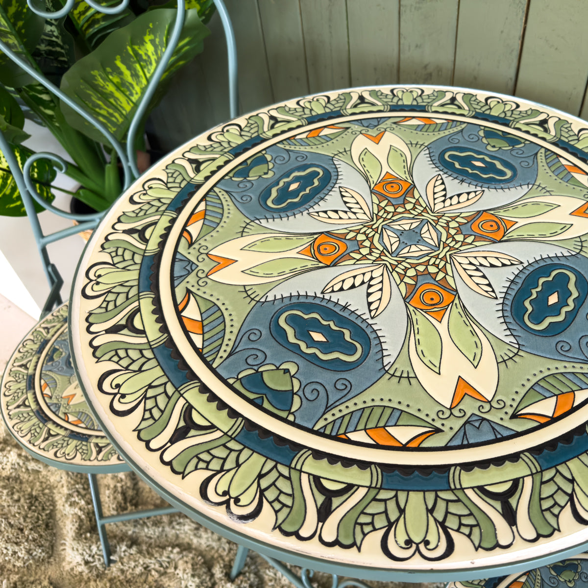 Decorative round patio table with intricate paisley design on a patio setting