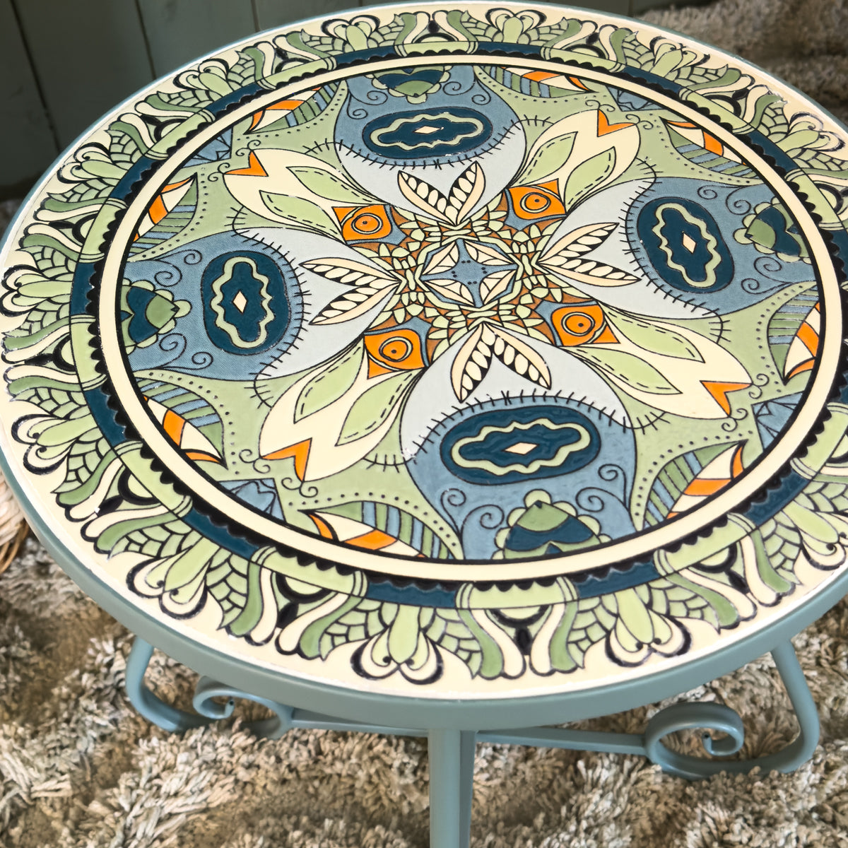 Decorative patterned round side table with intricate mandala design on a textured surface