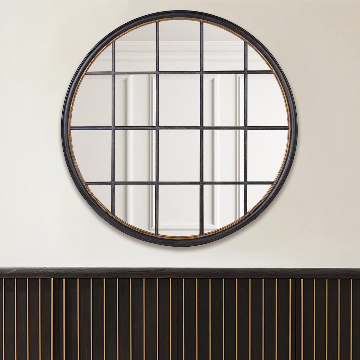 A black circular window mirror above a black slatted sideboard.