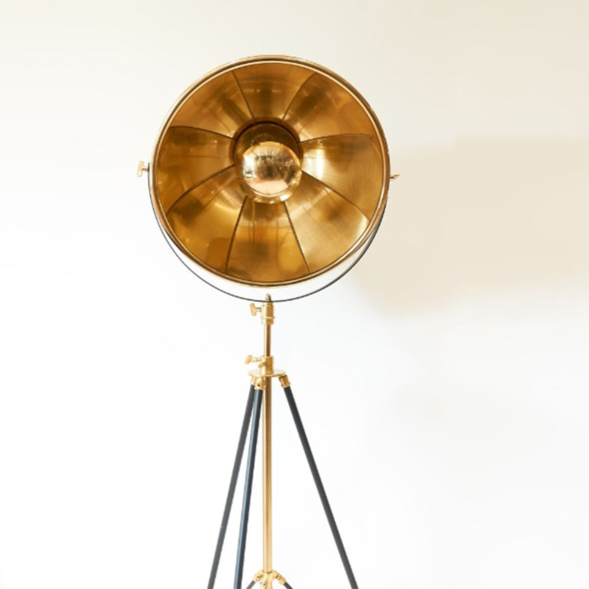 Gold floor lamp with a tripod base on a white background
