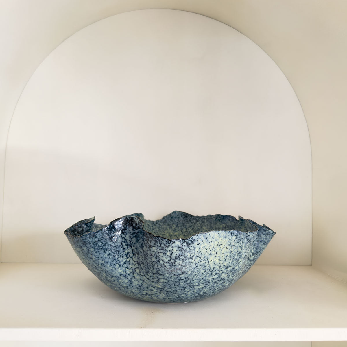 Blue speckled ceramic bowl on a white shelf