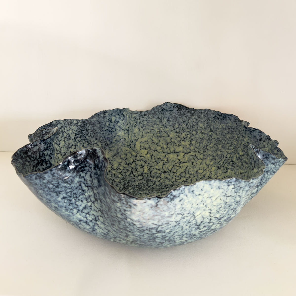 Speckled green and blue ceramic bowl on a white background
