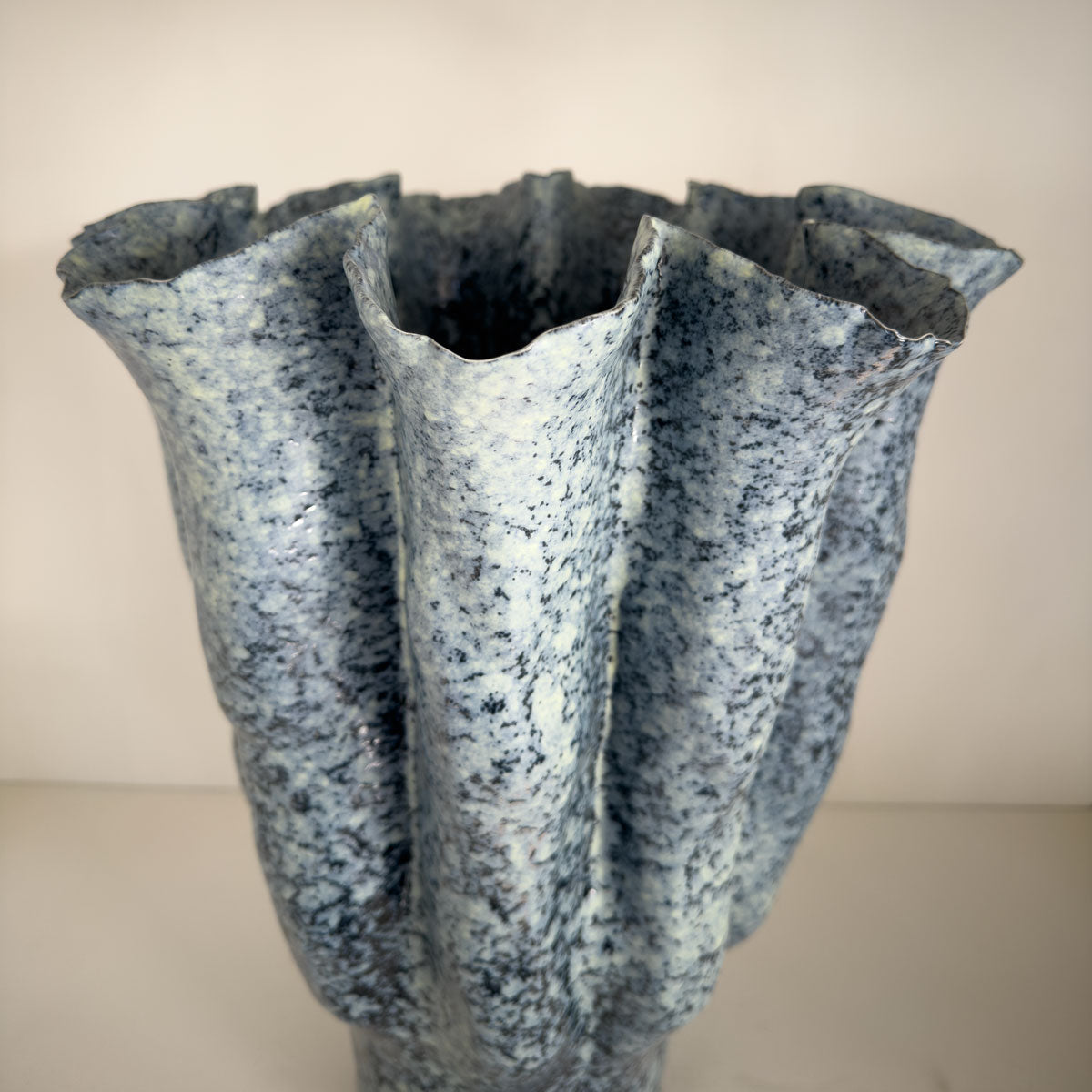 Textured blue vase with a unique design on a plain background