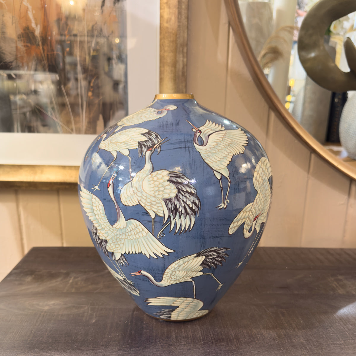 Decorative vase with crane patterns on a wooden surface
