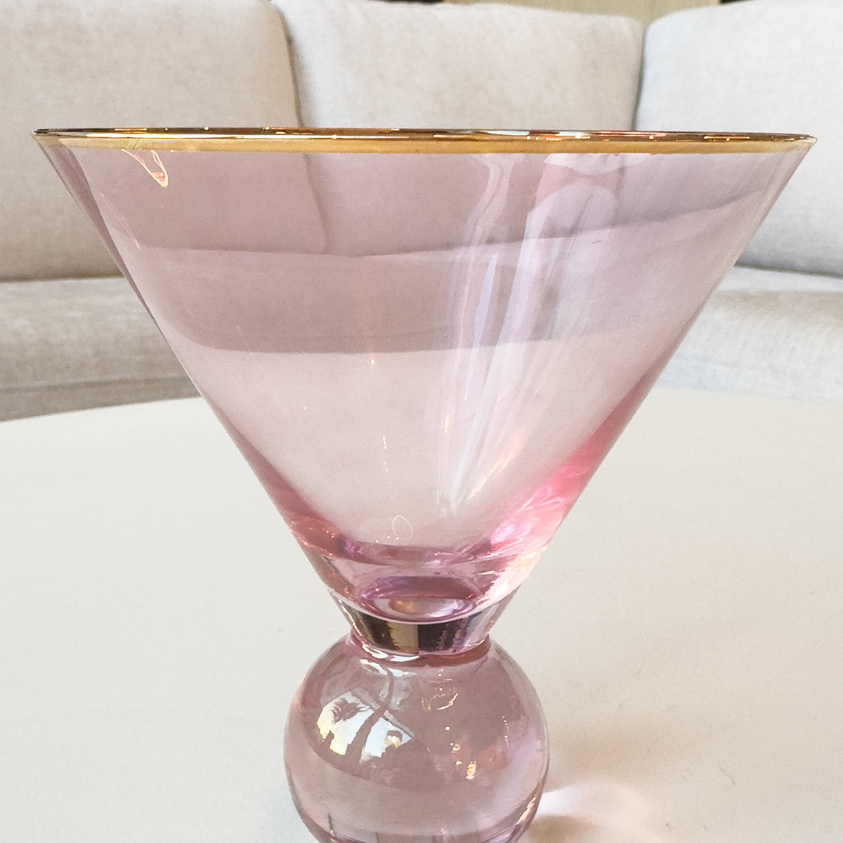 Pink martini glass with gold rim on a white surface