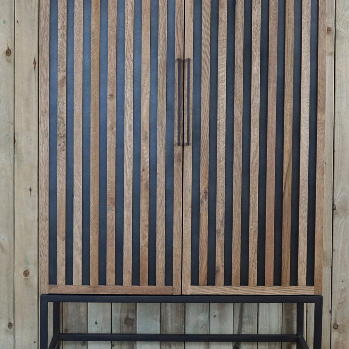 Wooden cabinet with black and natural wood slats against a wooden background
