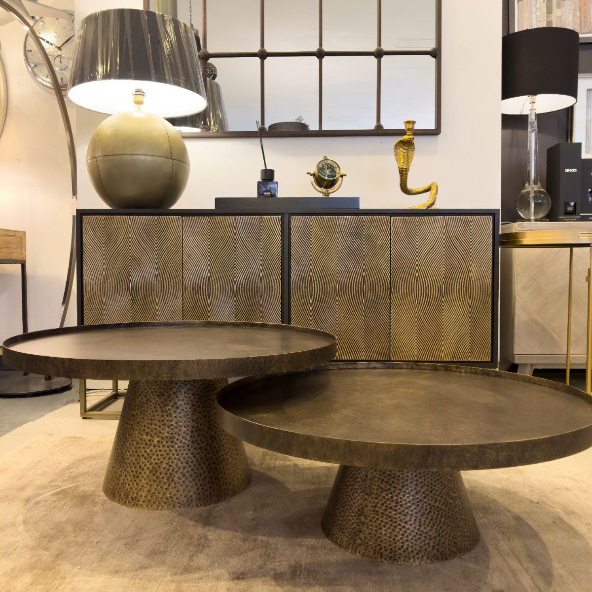 Two bronze coffee tables in a stylish interior setting with decorative items.