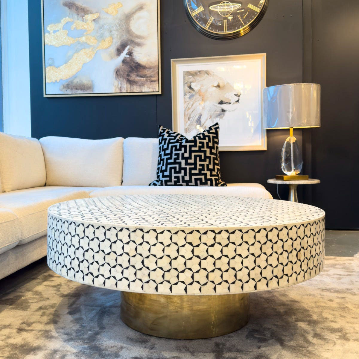 Modern living room with a round patterned coffee table, beige sofa, and decorative wall art.