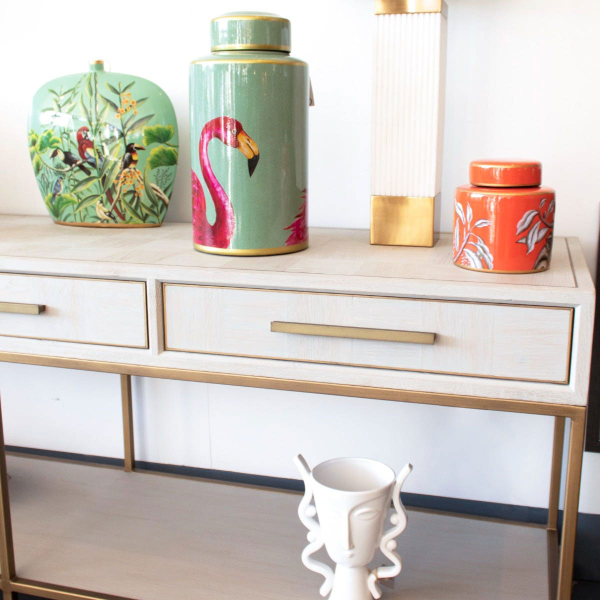Decorative vases on a cream console table with a white wall background