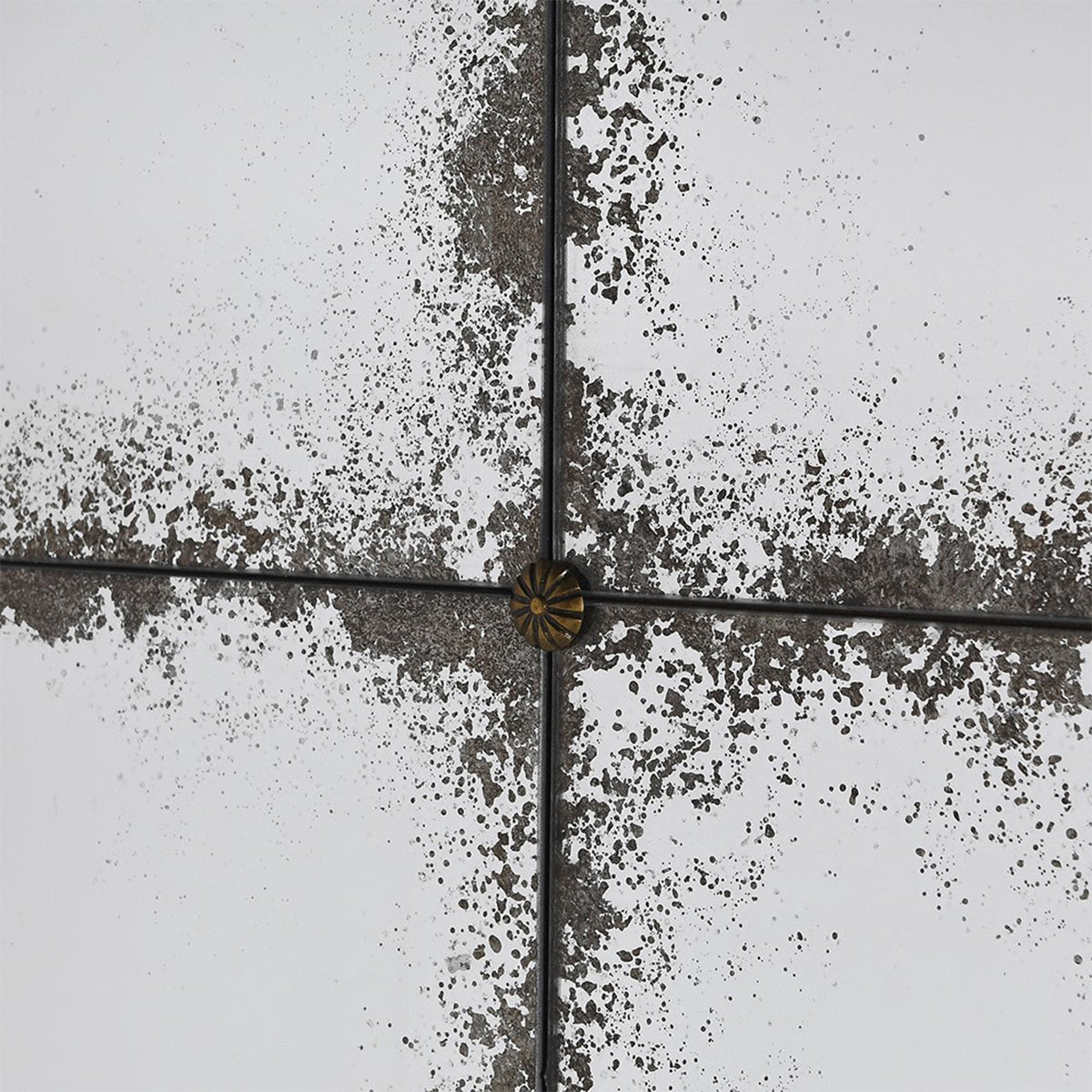 A close up of a distressed glass grid mirror with gold buttons seperating the panes.
