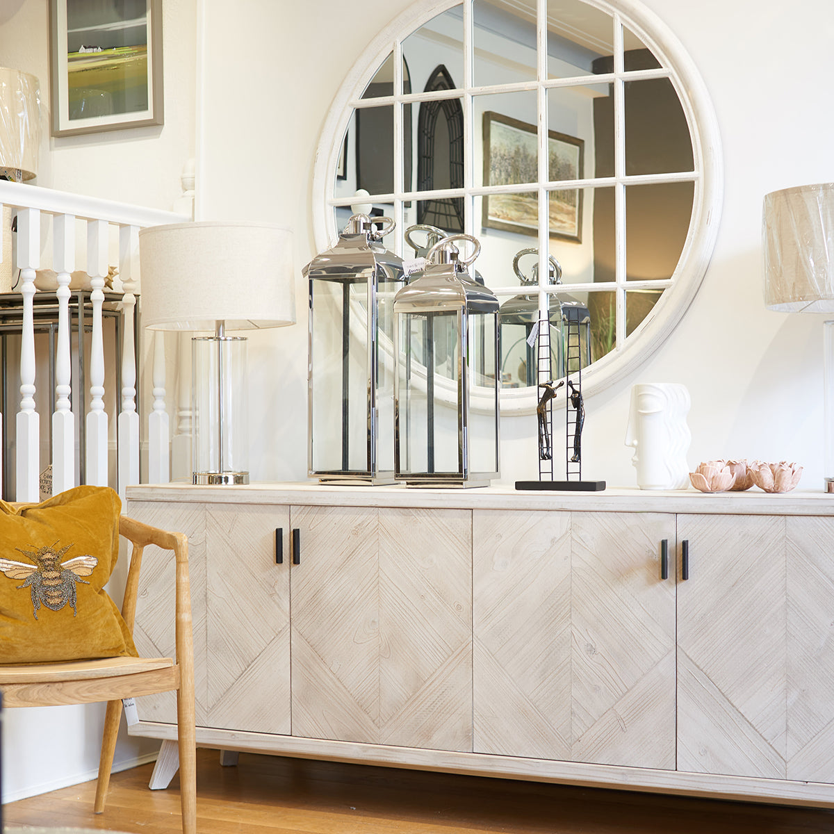 White cabinet with decorative items and a round mirror in a room.