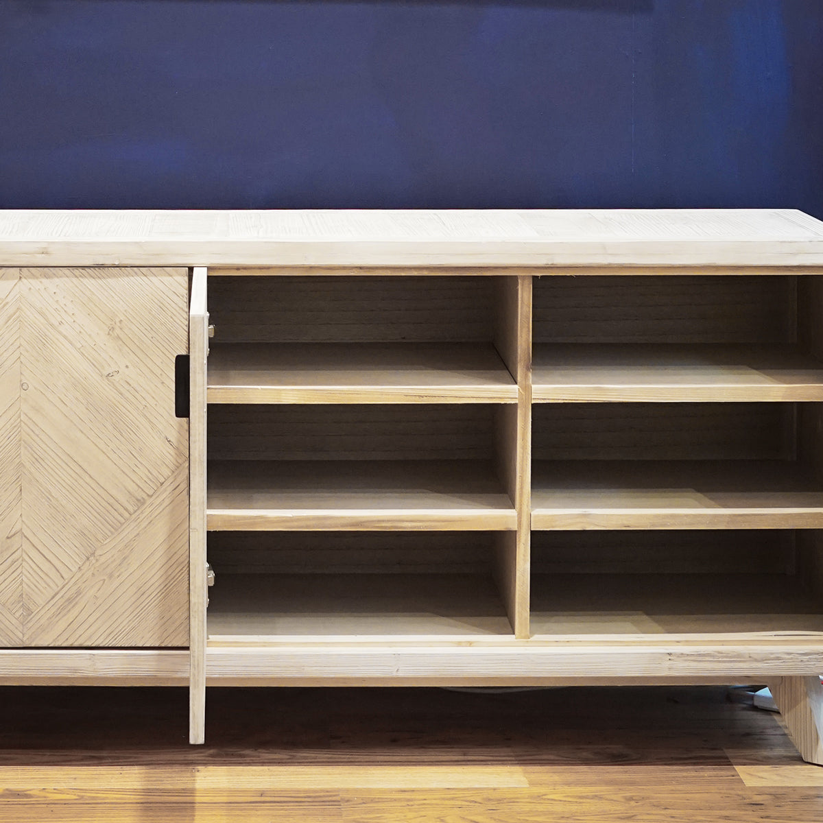 Wooden sideboard with a herringbone pattern on a blue wall background
