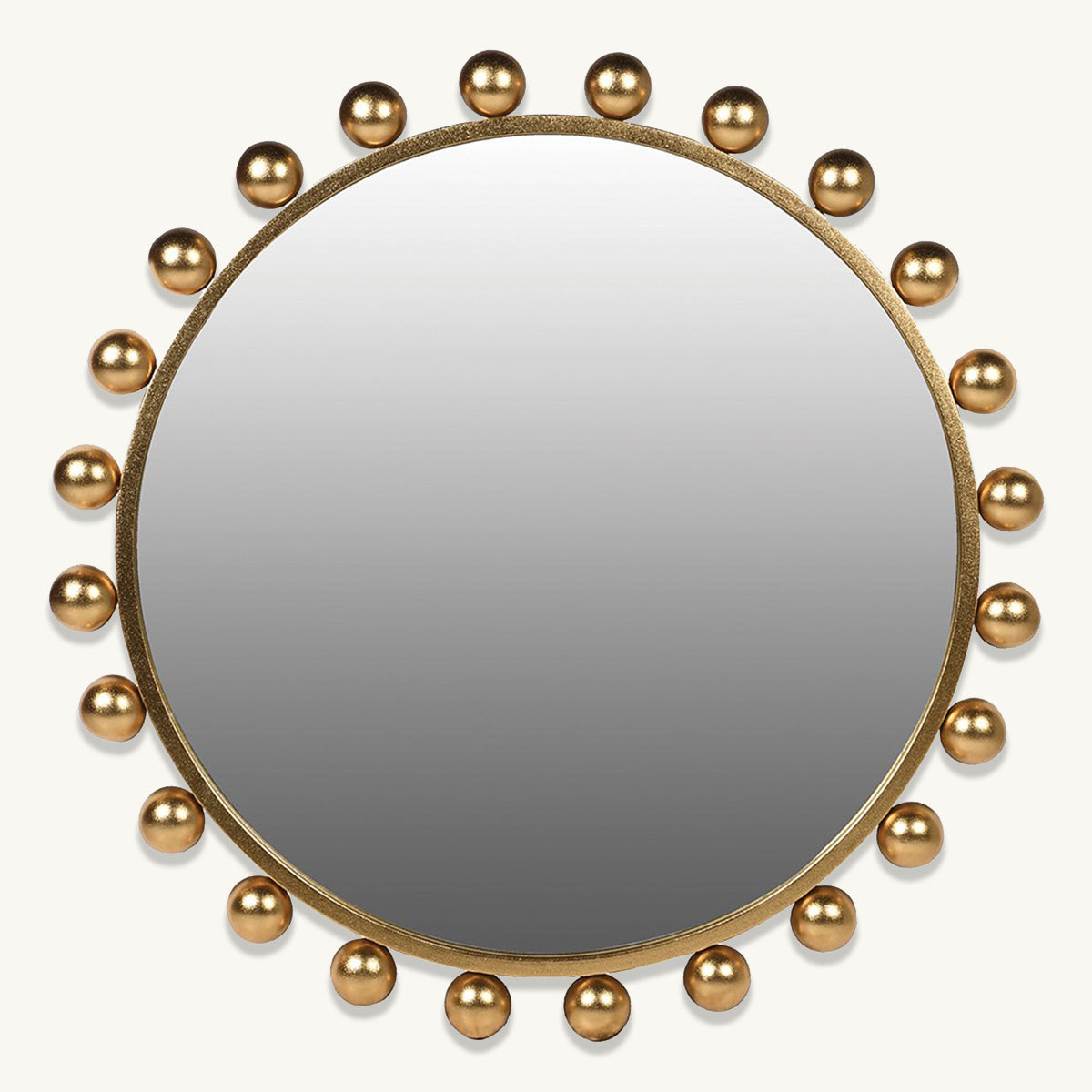 A round wall mirror with gold bobbles surrounding the frame.