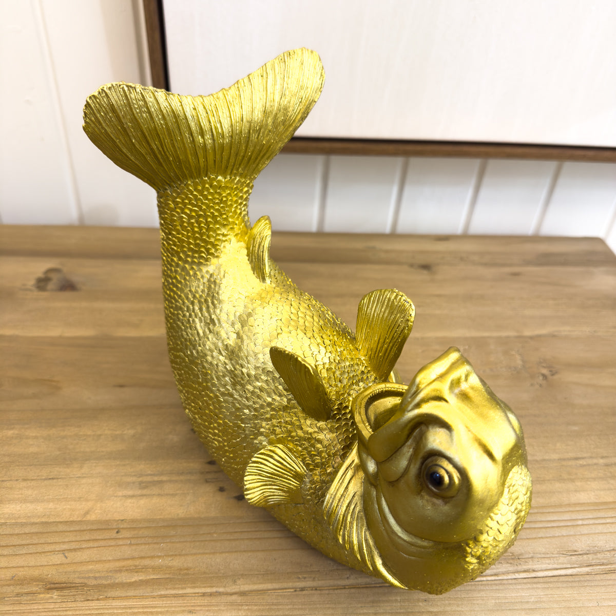 Gold fish-shaped object on a wooden surface