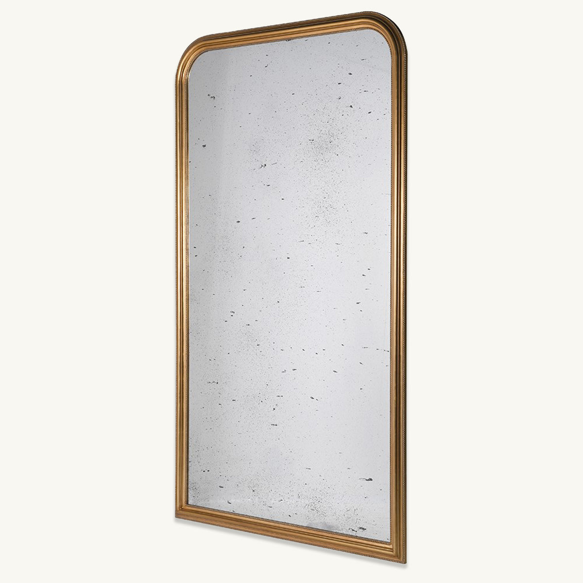 An oversized statement mirror with a distressed gold frame and an arched design.