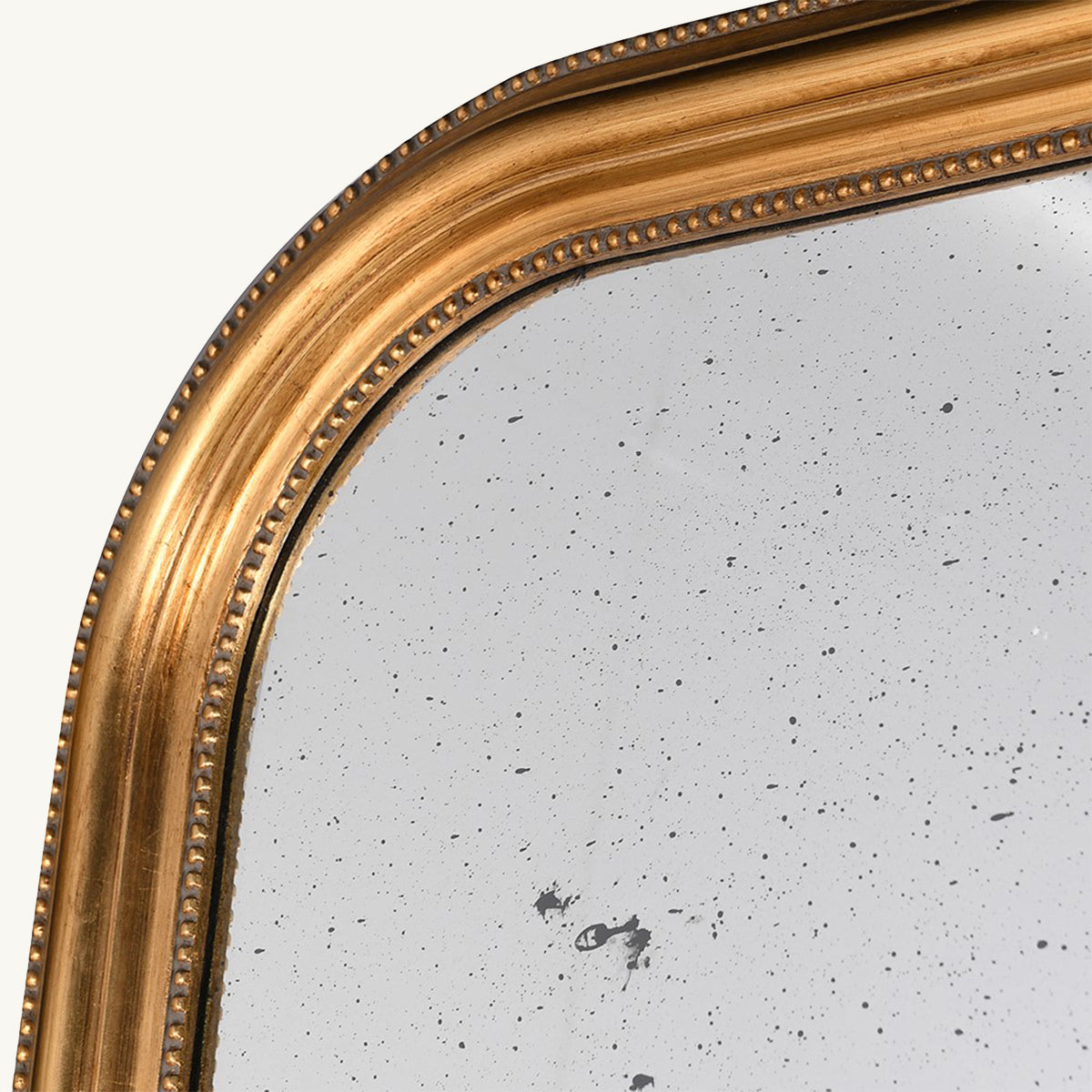 A close up of a gold arched mirror with distressed glass