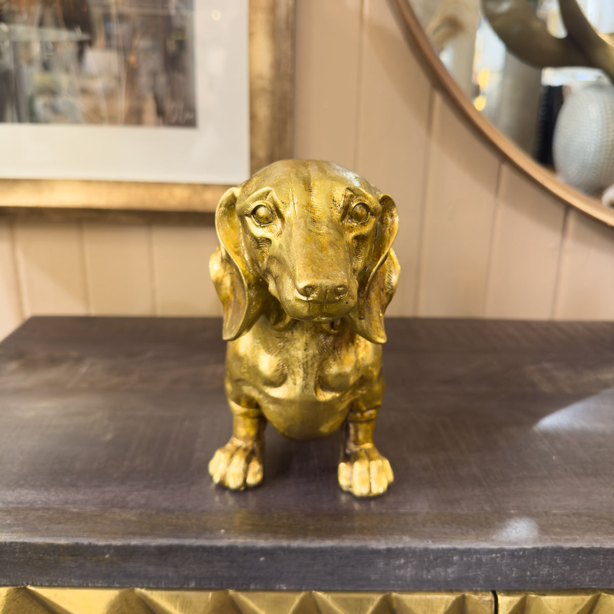Gold dog sculpture on a dark surface with a blurred background