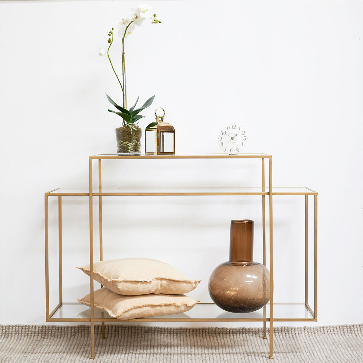 Gold metal console table with decorative items on a white background