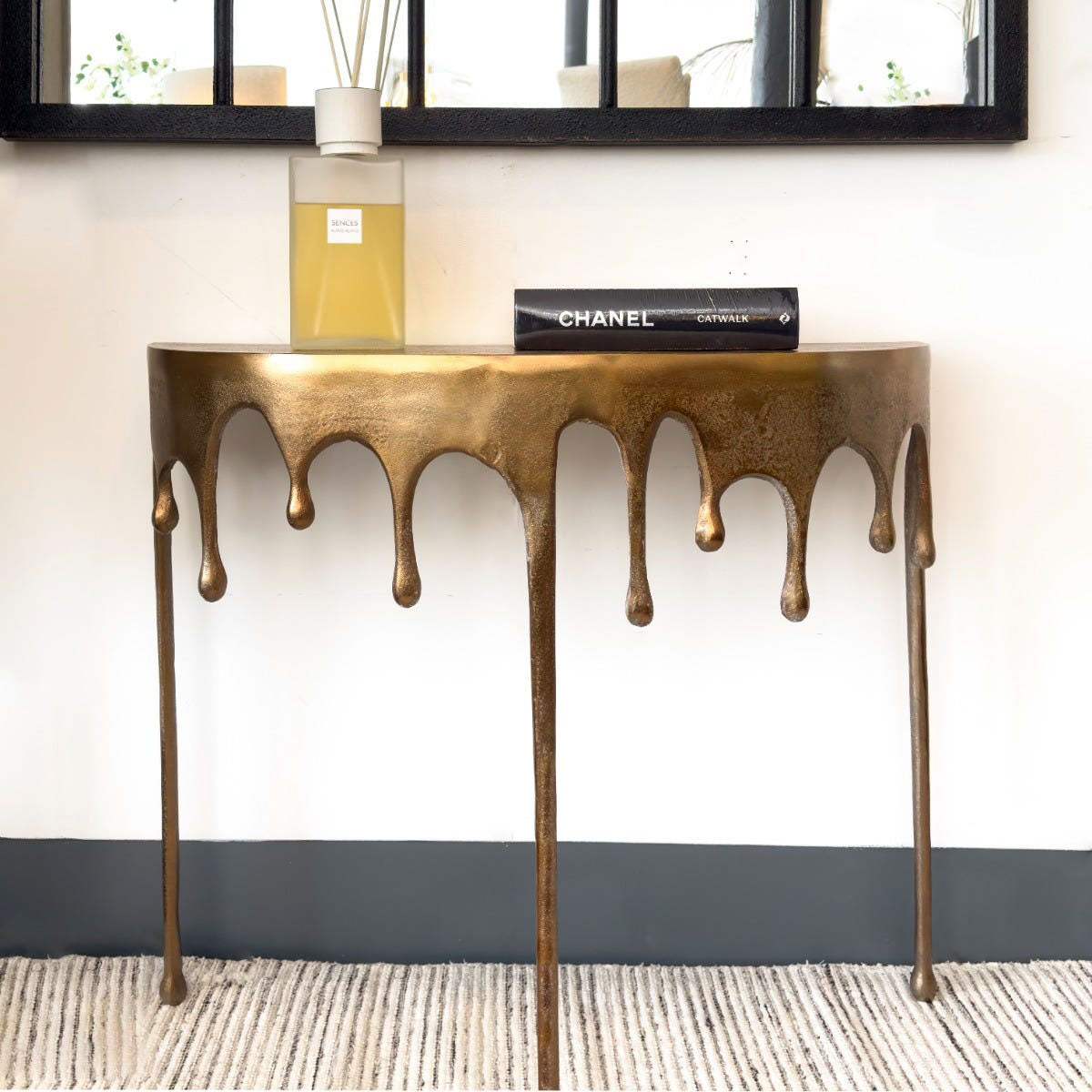 Bronze console table with decorative design against a white wall.
