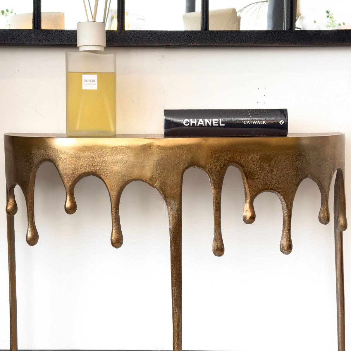 Gold drip console table with decorative elements on a white wall background