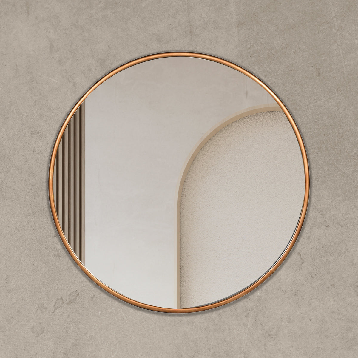A golden framed circular mirror hanging on a beige concrete wall.