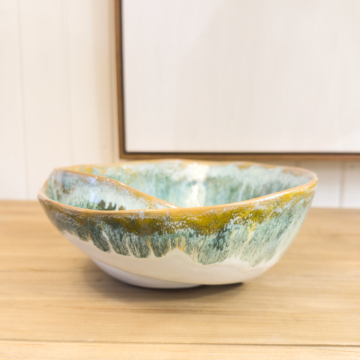 Ceramic bowl with green and gold glaze on a wooden surface