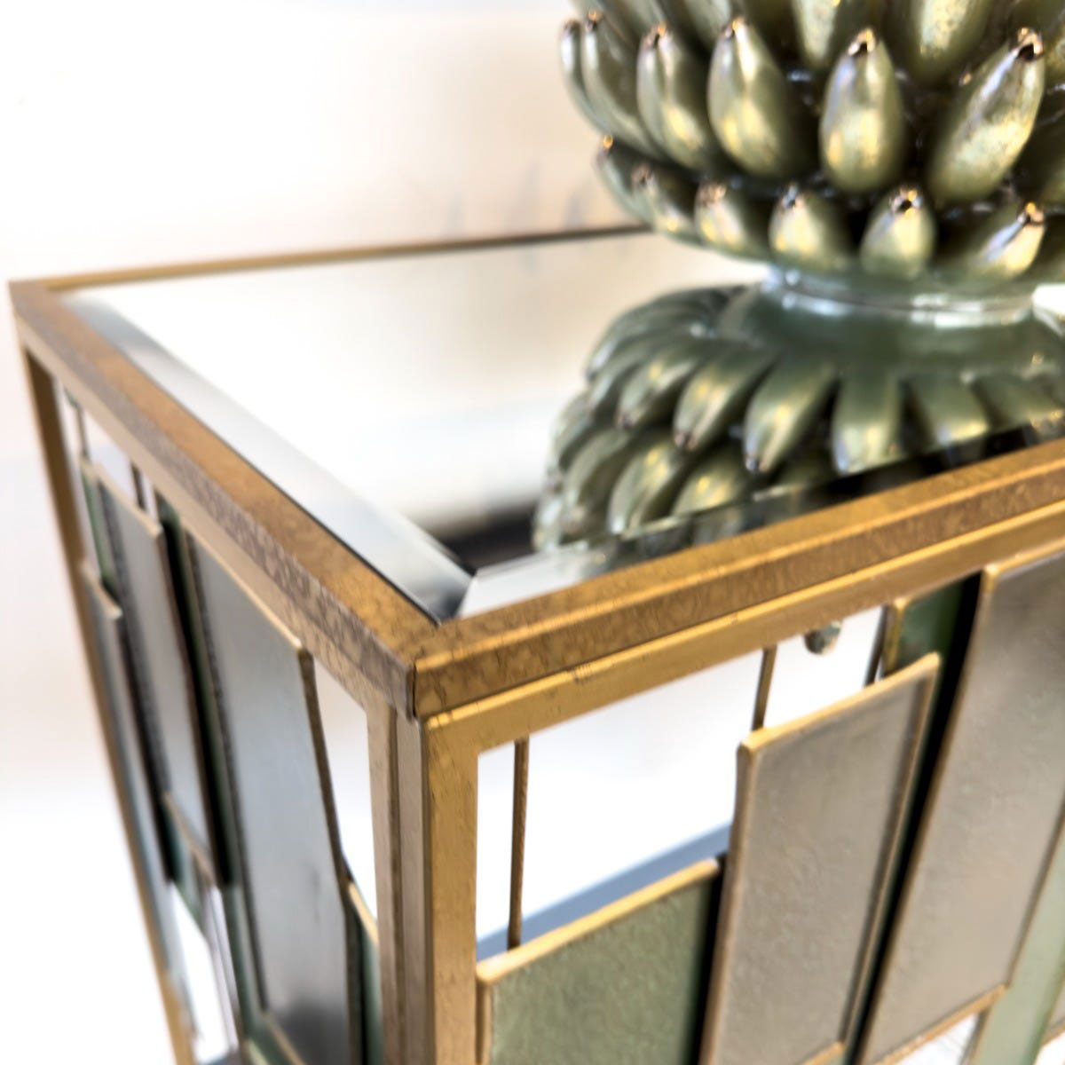 Decorative green console table with gold frame and mirror surface, featuring a green decorative item.
