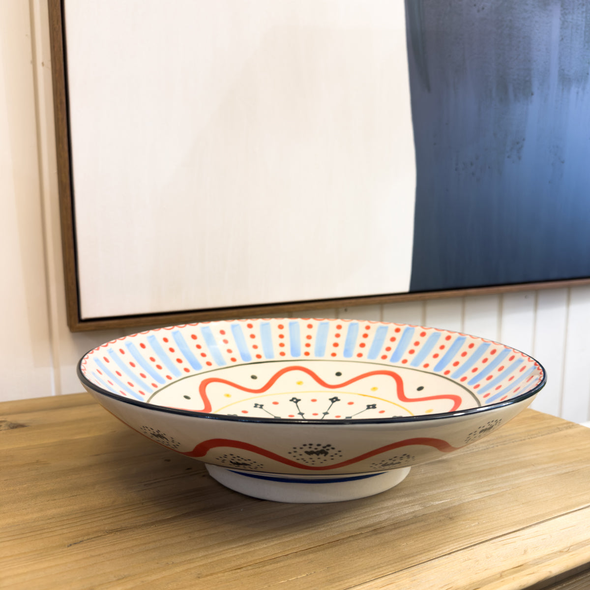 Decorative ceramic bowl with colorful patterns on a wooden surface.