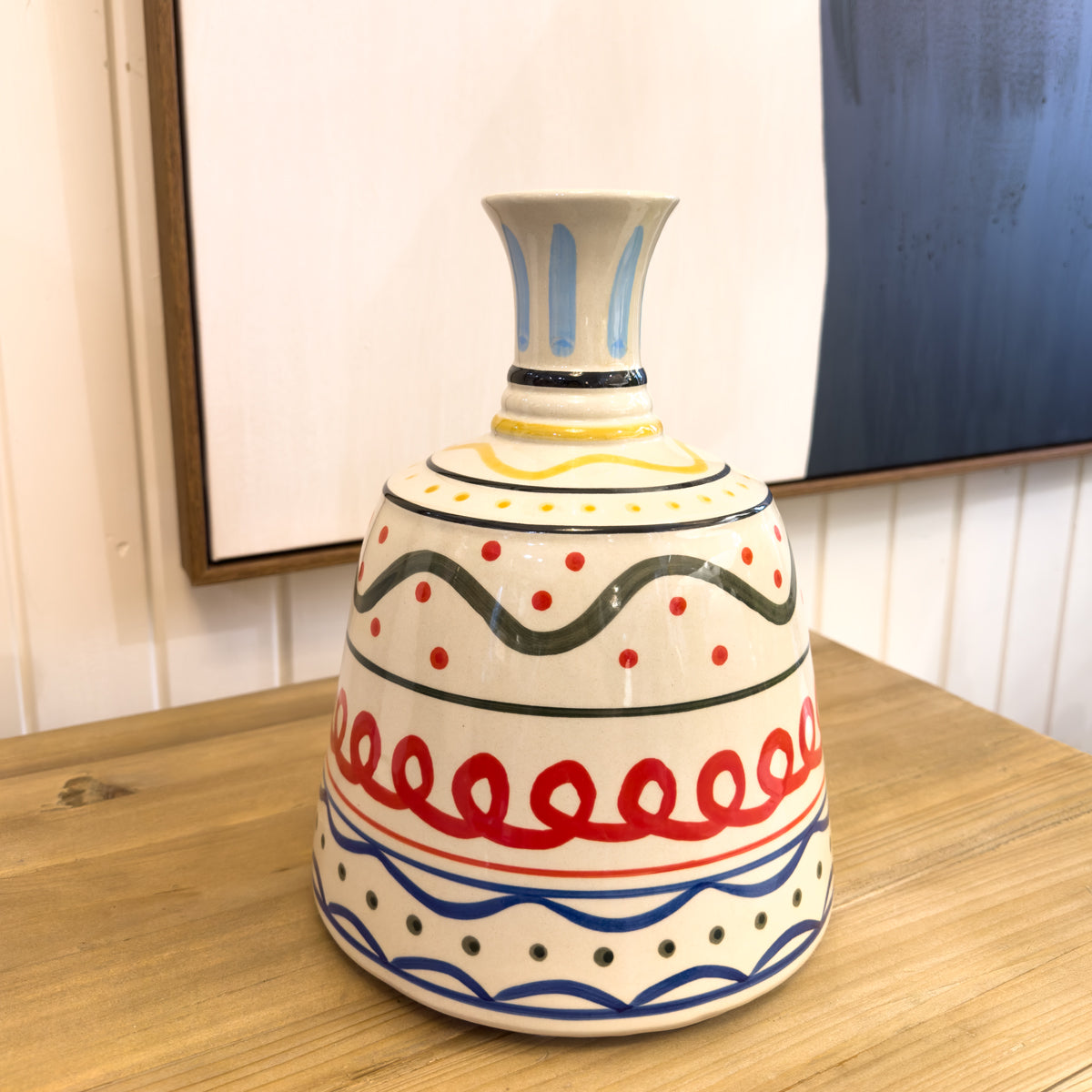 Decorative ceramic vase with colorful patterns on a wooden surface.