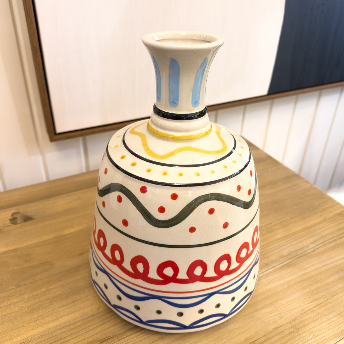 Decorative ceramic vase with colorful patterns on a wooden surface