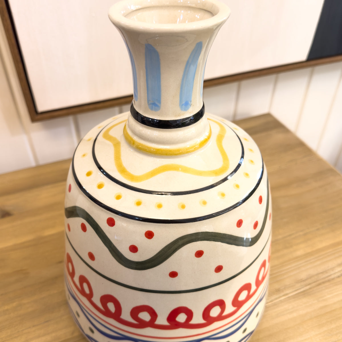 Decorative ceramic vase with colorful patterns on a wooden surface