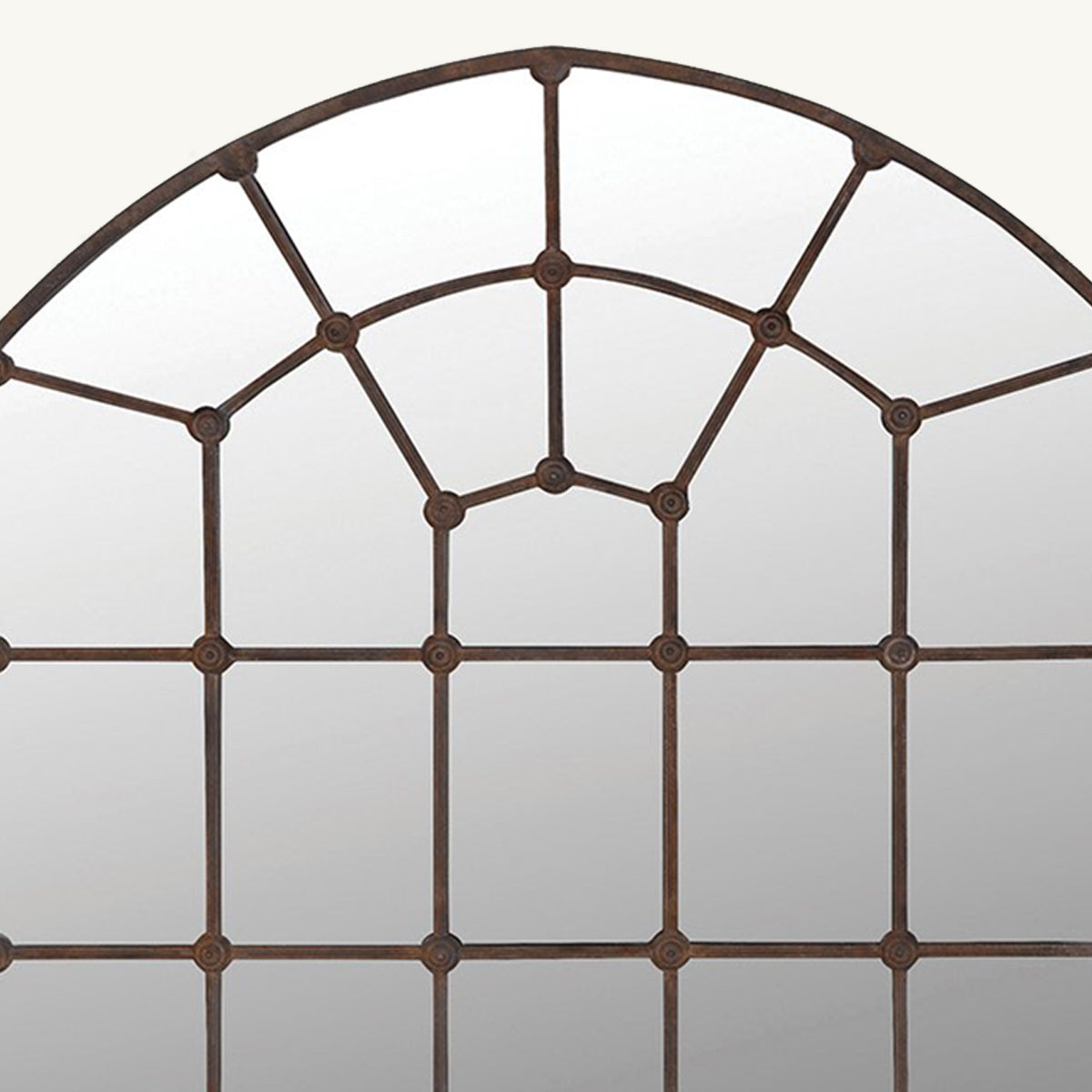 A close up of an arched window pane mirror with a rustic brown iron frame.