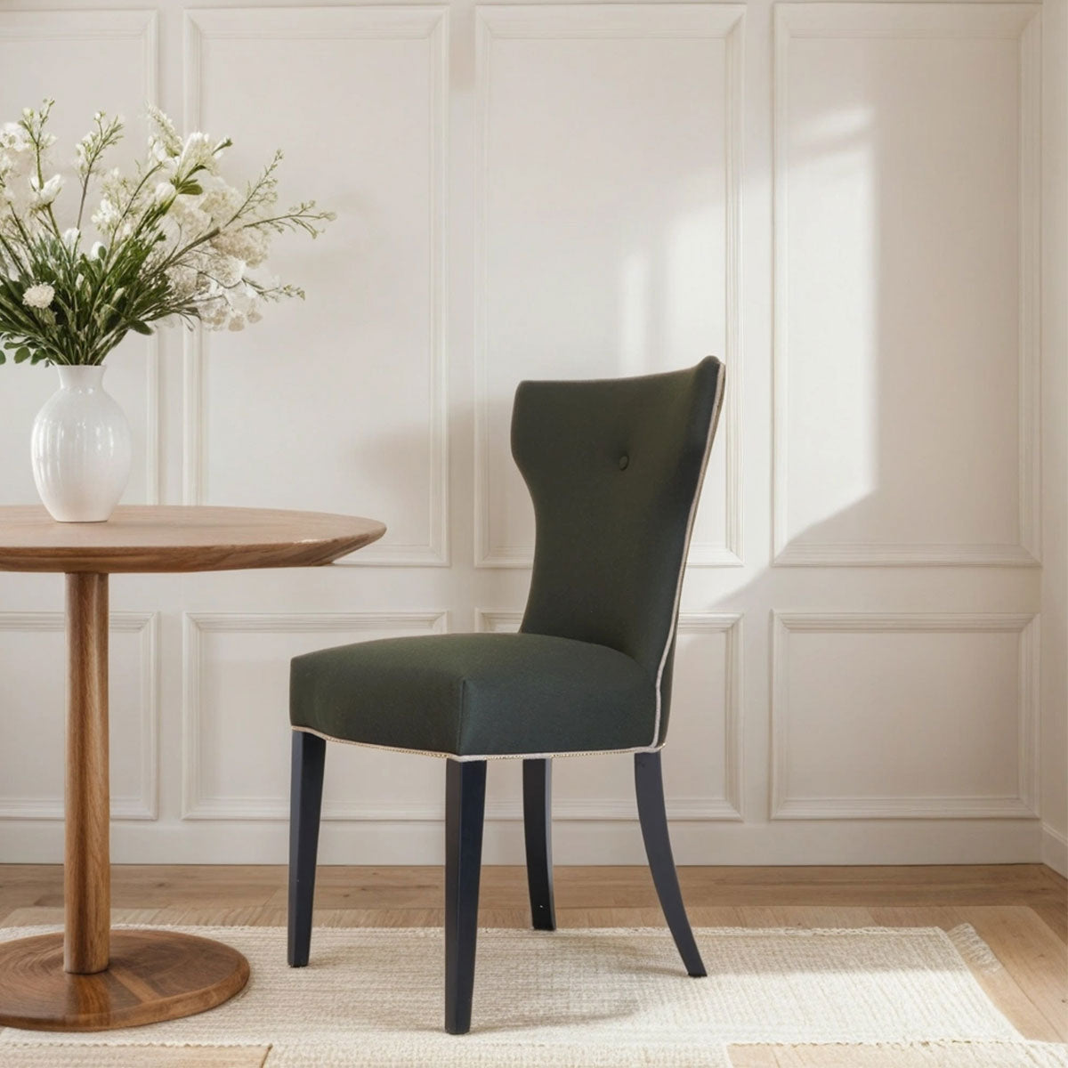 Green chair in a room with a wooden table and white flowers.