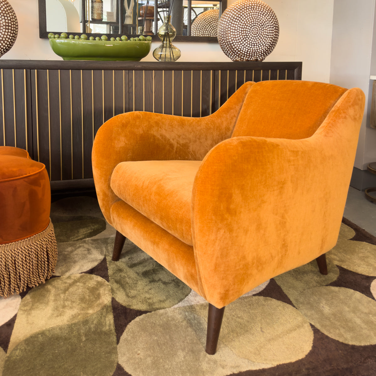 Orange armchair in a room with decorative elements and a patterned rug.