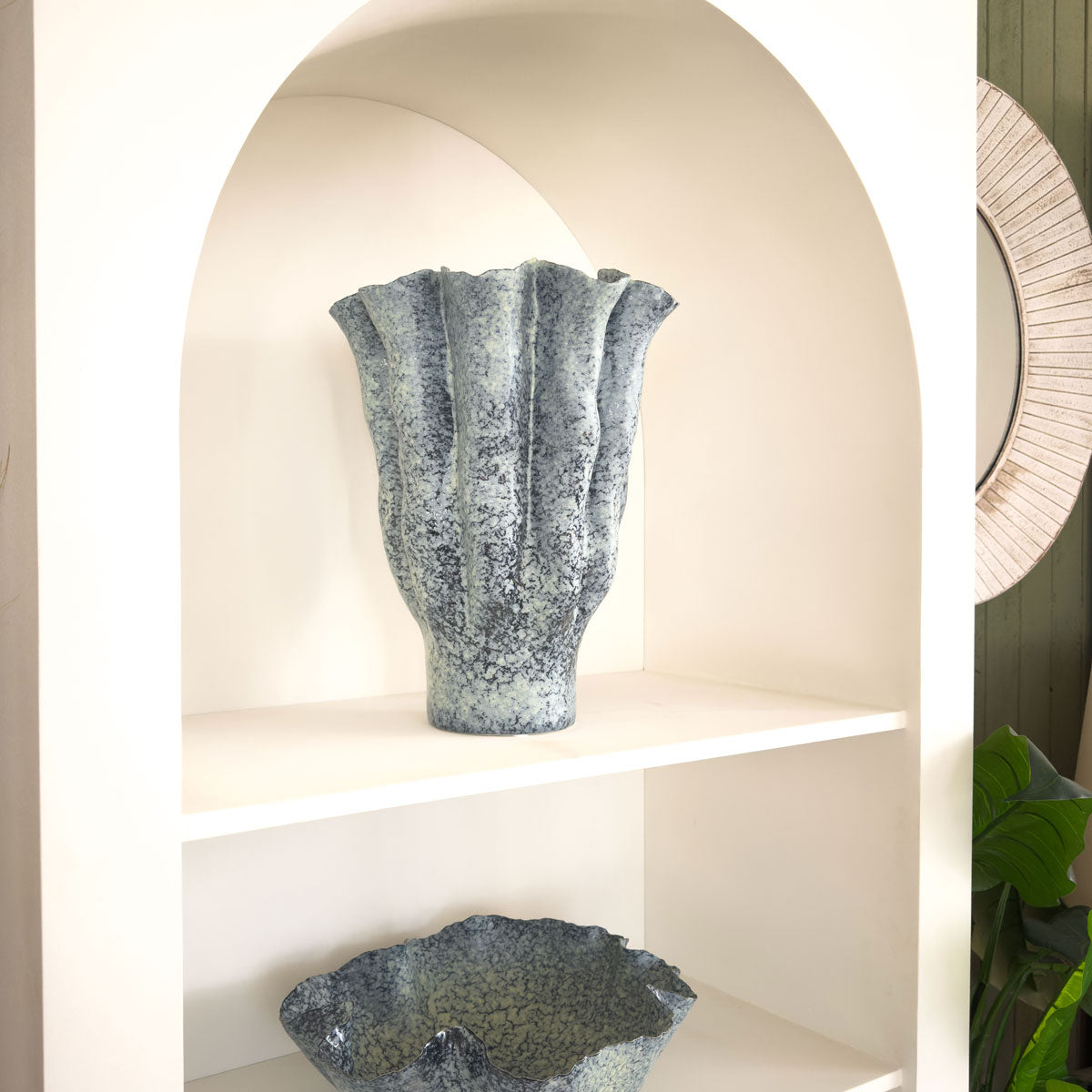 Decorative stone vases on a shelf with a neutral background